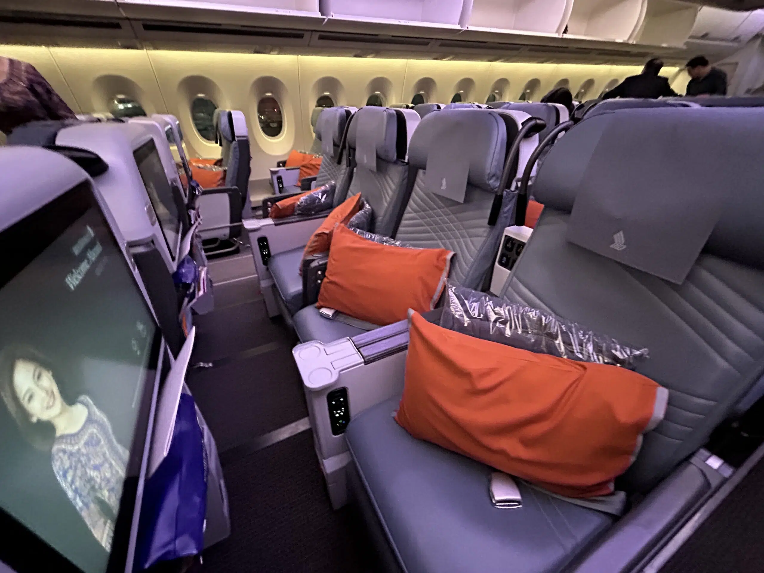 a row of empty airplane seats with orange pillows