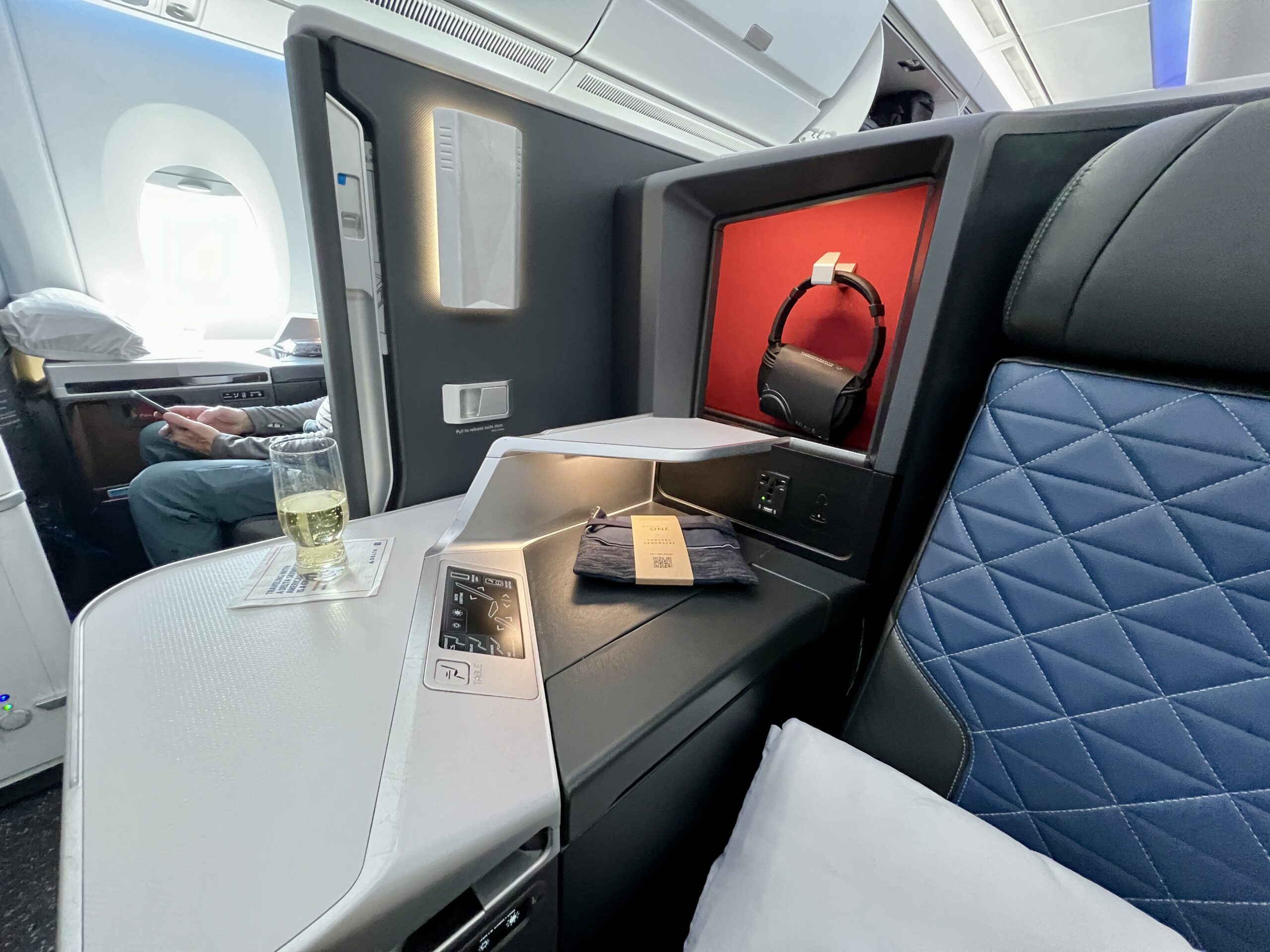 console table inside business class suite with a glass of champagne