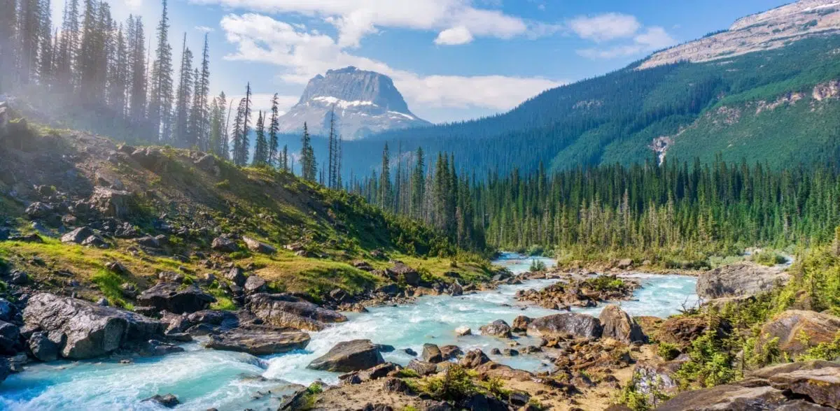 A large waterfall over a body of water with a mountain in the background