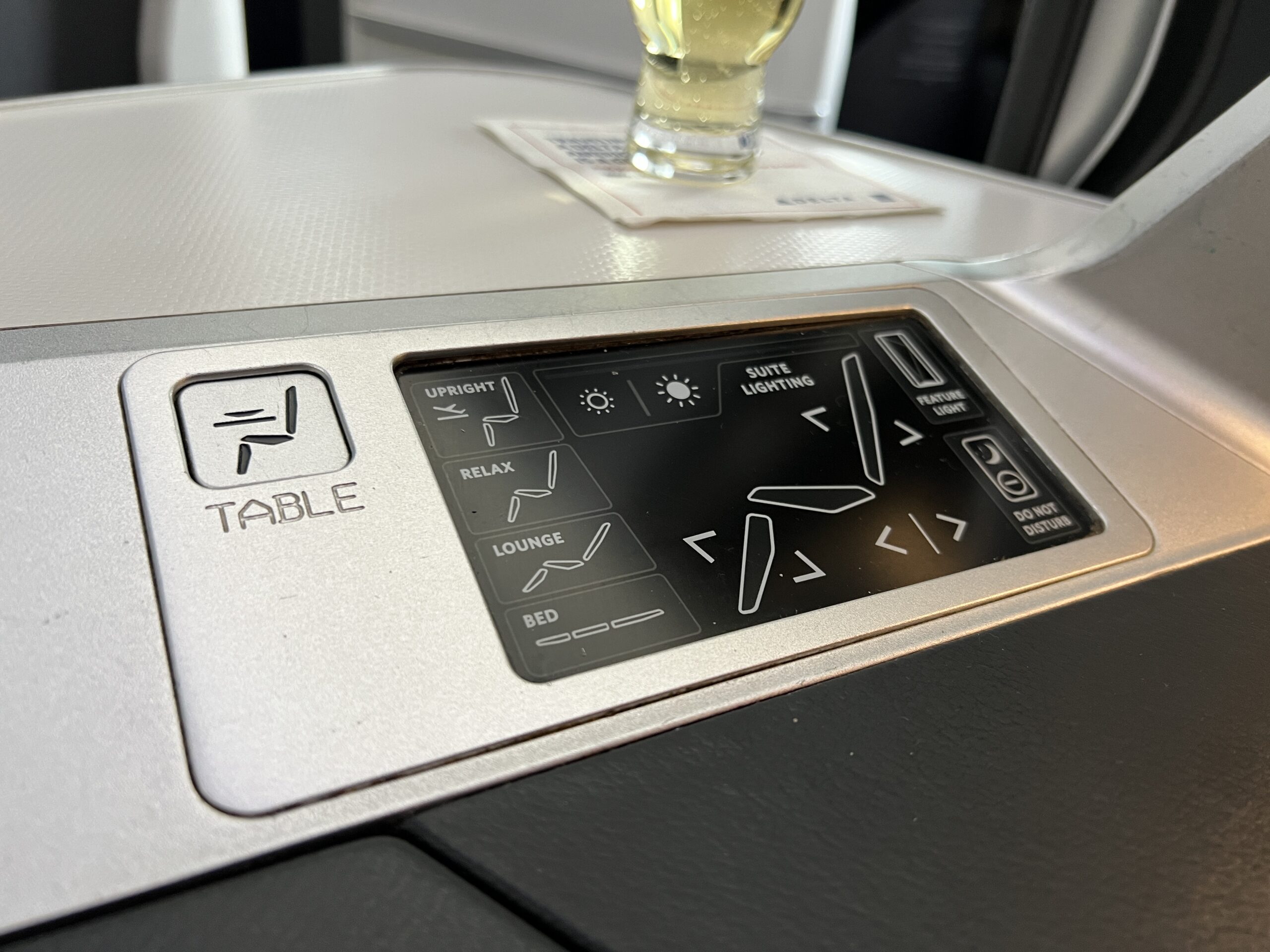 business class seat controls with a glass of champagne