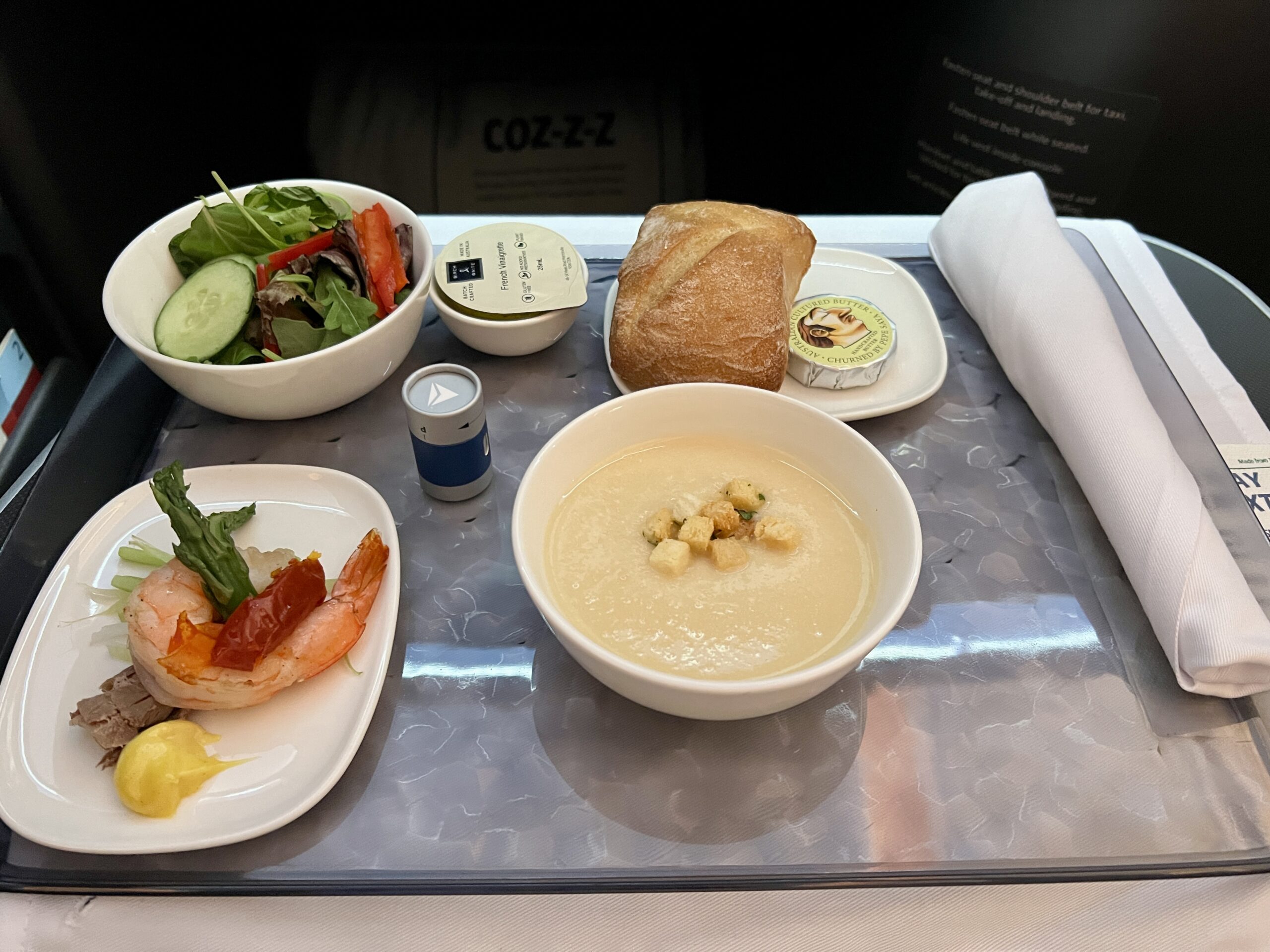 a tray with shrimp, salad and soup